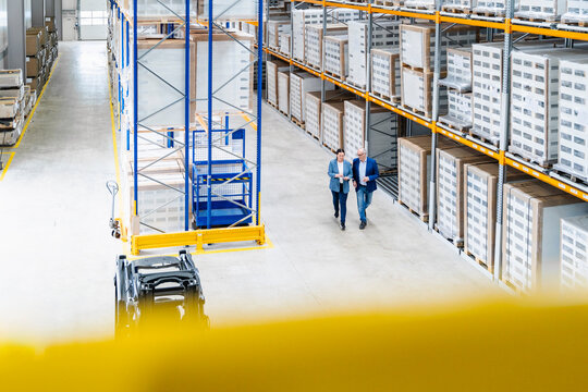 A woman and a man discuss logistics in a warehouse