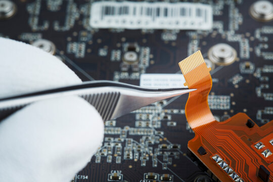 Human hand repairing printed circuit board, close up