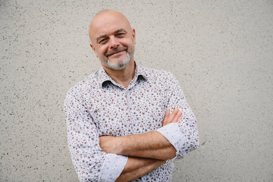 Confident male doctor smiling against a concrete wall