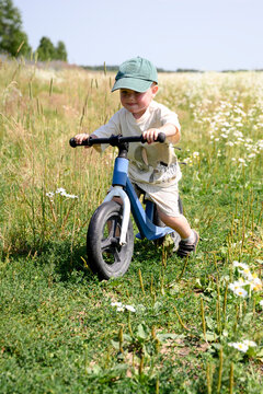A smiling boy rides a bike through a summer flower field