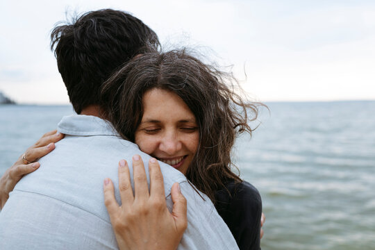 A happy couple hugs each other at the beach during summer vacation