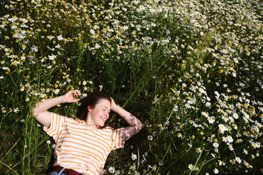 A smiling woman enjoys a summer meadow filled with beautiful flowers