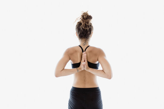 Woman practices reverse prayer yoga pose indoors for flexibility