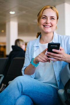 Smiling businesswoman holds smartphone in airport