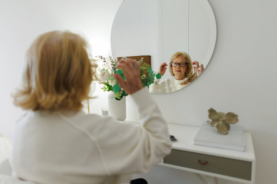 Smiling woman reading and relaxing at home in front of mirror
