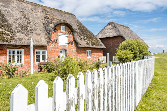 Thatched roof house with white fence in Hallig Langeness