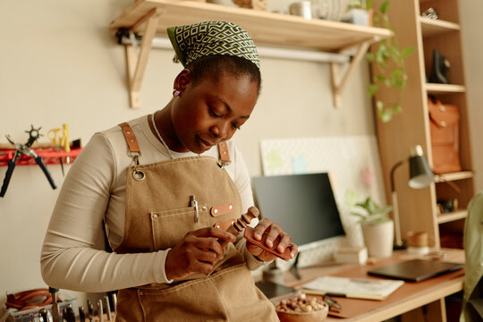 Female artisan crafts handmade leather detail in her workshop