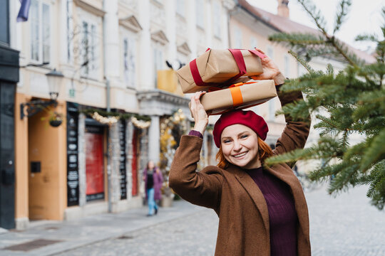 Playful woman holds wrapped gift on her head at a Christmas market