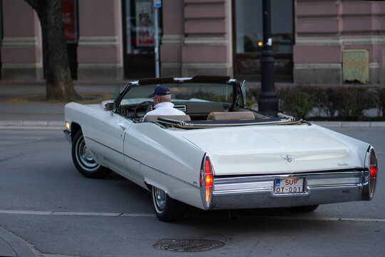 Cadillac DeVille Convertible 1968 white fullsize vintage open top car oldtimer driving rear three quarter view on city street, Subotica, Serbia, Jul 4,  2026