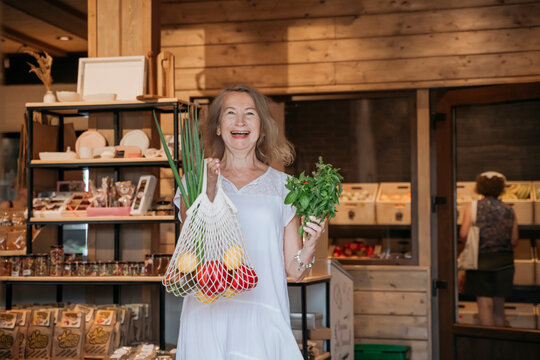 Smiling woman holds a bag of fresh vegetables in a store