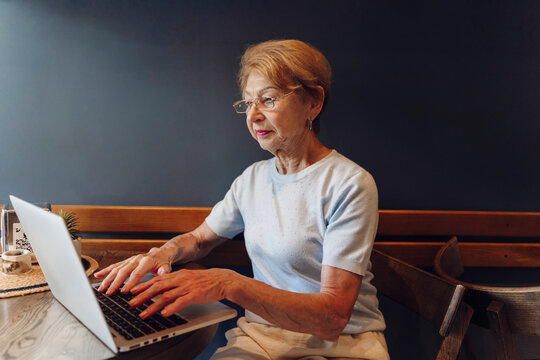 Woman types on a laptop computer at an indoor cafe