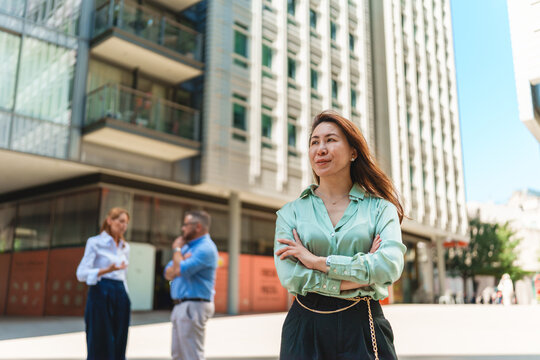 Confident businesswoman stands outdoors near modern city building