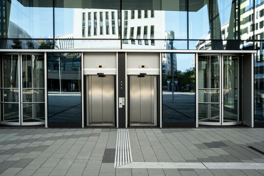 Symmetrical modern building entrance with glass doors and metal exterior geometry that repeats across the entrance and shapes the building architecture