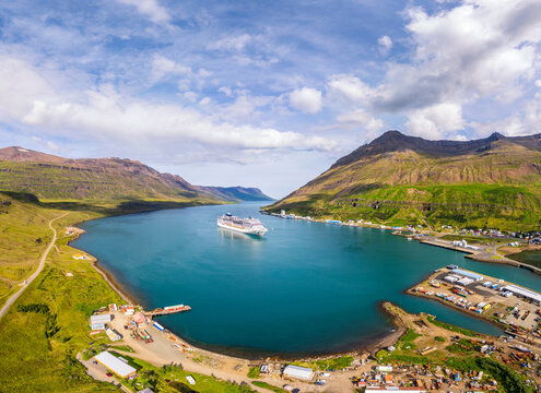 A cruise ship navigates the calm waters of Sey�isfj�r�ur fjord