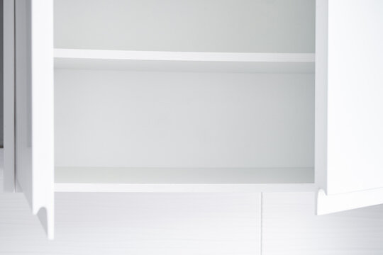Empty kitchen cupboard with clean white shelves