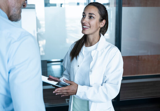 Smiling female doctor advises male patient with tablet in practice