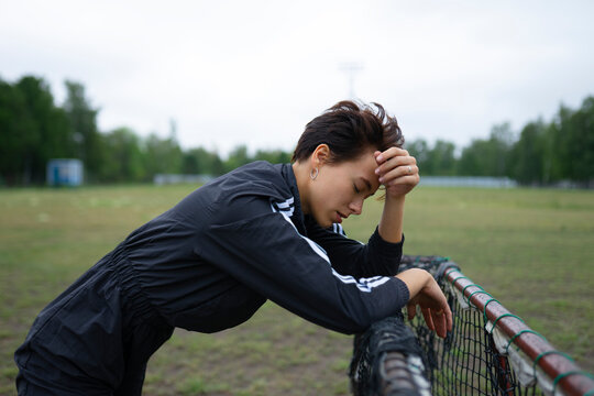 Exhausted female athlete leans on a goal net