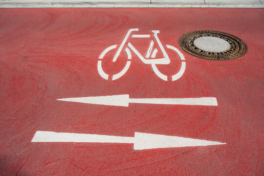 Red bicycle lane shows painted white direction arrows on the street