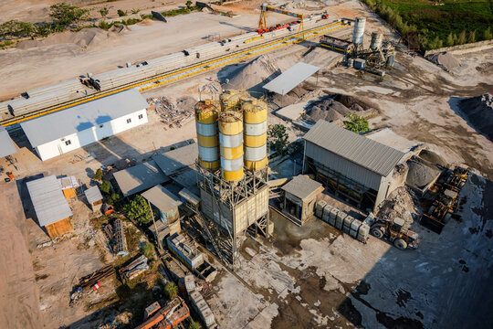 Aerial view of a concrete batching plant with tall yellow silos, industrial machinery, and stockpiles of gravel in Semarang Regency, Central Java, Indonesia.