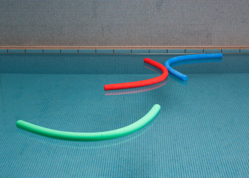 Aqua noodles floating on water of indoor swimming pool
