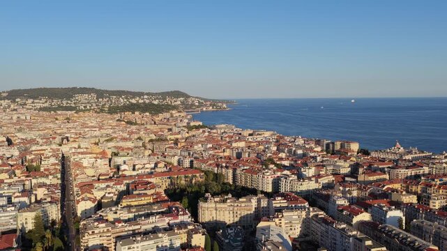 Static wide panorama over red rooftops to Baie des Anges, Negresco dome, Castle Hill and Mont Boron headland, golden light, Nice, French Riviera, Cote d Azur, France