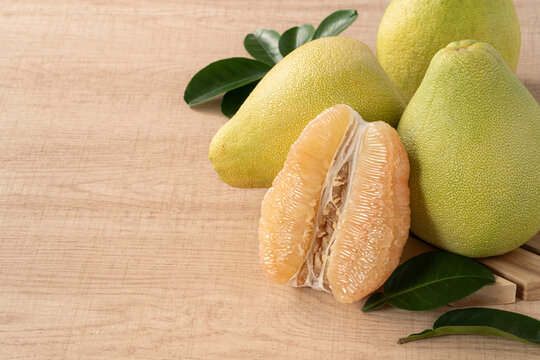 Fresh pomelo fruit with leaf on wooden table background.