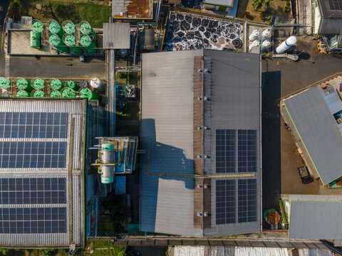 Aerial view of an industrial facility featuring solar panels on rooftops, green storage tanks, and wastewater treatment infrastructure in Banyumas Regency, Central Java, Indonesia.