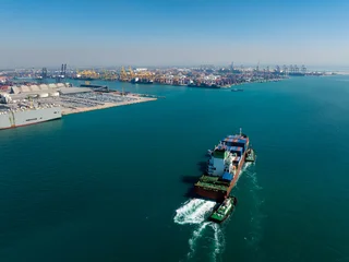 Large Container Ship Escorted By Tugboats Navigates Turquoise Waters Toward Shipping Terminal Docks In Laem Chabang Chon Buri Thailand For Global Trade Distribution © SHUTTER DIN