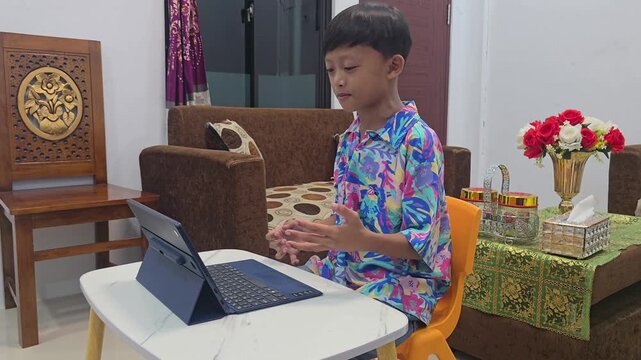 Cheerful Asian student talking and making active hand gestures during a virtual online class video call using a tablet