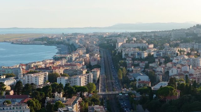 Telephoto aerial of the coastal expressway and railway, traffic, pebble beach and airport runway in hazy evening light, Nice, French Riviera, Cote d Azur, France