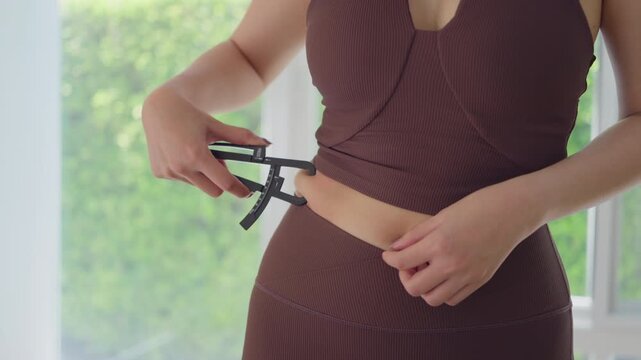 Rear view people young adult asian woman self caliper measure waist size shape lean body mass index fat track weight loss perimenopause life anti aging diet preventive modern medicine asia health care