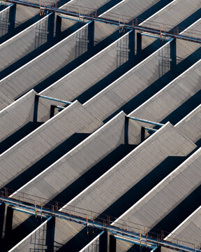 Aerial view of the saw-tooth roof structure of an old warehouse with repeating geometric patterns and deep shadows in Warsaw, Masovian Voivodeship, Poland.