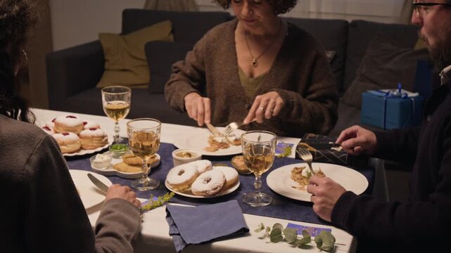 Caucasian Jewish family eating traditional Hanukkah meal during holiday dinner at home. Clip ideal for festive campaigns, cultural celebration promotions, and family winter marketing videos