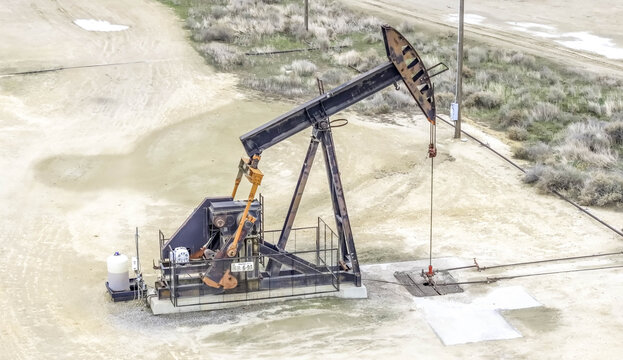 Aerial view of a pumpjack oil pump operating in a dry, sandy field in Oxnard, California, United States.