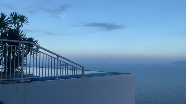 Luxury rooftop infinity pool overlooking Nha Trang bay blue sea and islands at twilight