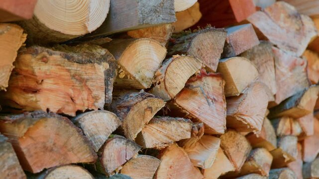 Firewood logs stack timber pile prepared for winter heating system. Close up of chopped wooden blocks texture in rural outdoor storage, handheld pan right.