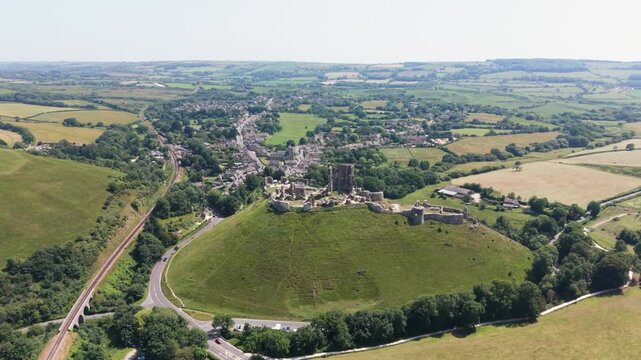 Corfe Castle Isle of Purbeck Dorset, England, flight over castle and village alongside Swanage to Corfe railway with views of the surrounding countryside on bright sunny day
