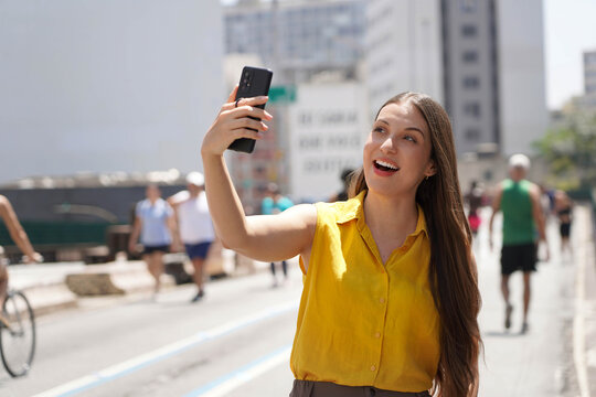 Self portrait of happy young woman using ring holder to avoid phone theft in the metropolis