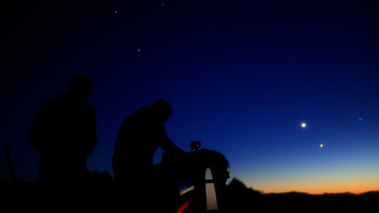 Amateur astronomers observing stars, planets, Moon and other celestial objects with a telescope in nature. © astrosystem