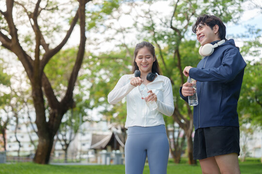 Asian runners taking water break in park for fitness lifestyle
