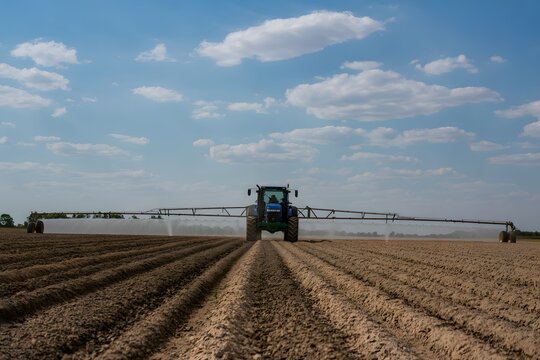 Modern Agricultural Tractor Spraying Cropland Under a Blue Sky