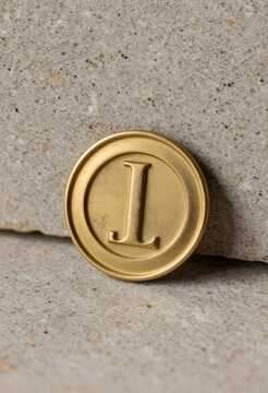 Branding and luxury identity, gold coin with letter l embossed on textured stone surface for premium corporate logo design and high end marketing
