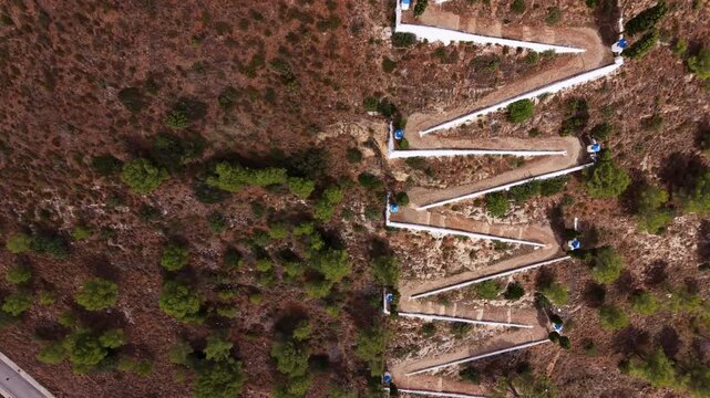 Top-down view of a whitewashed zigzag pathway lined with blue-domed Stations of the Cross climbing a dry hillside to the Hermitage of Saint Anthony, Sot de Ferrer, Valencia, Spain