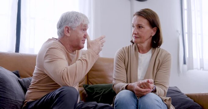 Senior Caucasian couple discuss ideas on living room sofa, using expressive hand gestures, attentive eye contact, and calm responses that convey communication, understanding, and lasting trust.