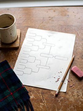 Hand-drawn tournament bracket on a rustic wooden table with a pencil and coffee.