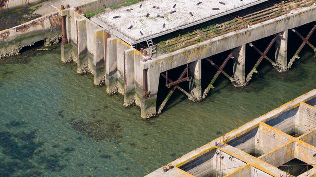 Aerial view of the historic concrete caissons at Inlaag Schelphoek, showing weathered structural supports and clear water in Serooskerke Schouwen, Zeeland, Netherlands.