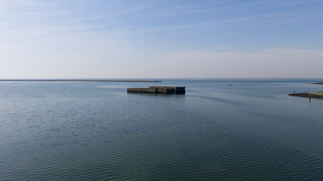 Aerial view of the historic concrete caissons at Inlaag Schelphoek, remnants of flood defenses, in the calm waters of the Oosterschelde estuary in Serooskerke Schouwen, Zeeland, Netherlands.