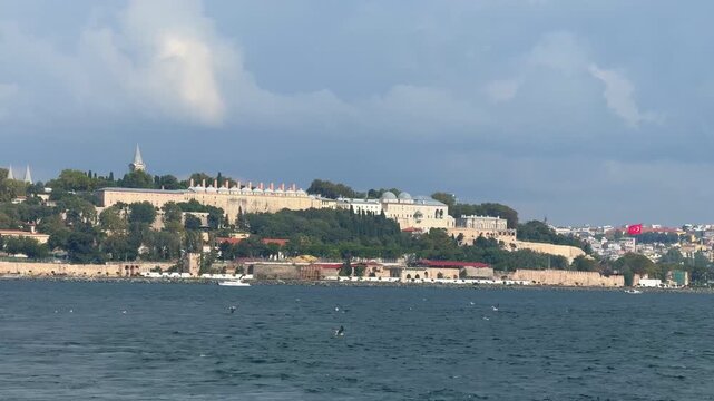 Topkapi Palace overlooks the Bosphorus waterfront in Istanbul, Turkey. Historic Ottoman landmark seen from water represents imperial heritage and tourism