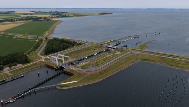 Aerial view of Zandkreeksluis lock system with boats moored in the channel, surrounded by green dikes, agricultural fields, and the Veerse Meer in Kortgene, Zeeland, Netherlands.