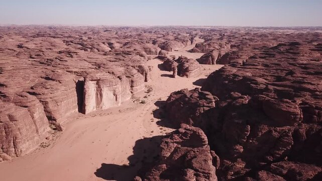 an expansive aerial view shows a sprawling desert landscape carved with deep canyons, rocky outcroppings, and sandy corridors stretching into the horizon.